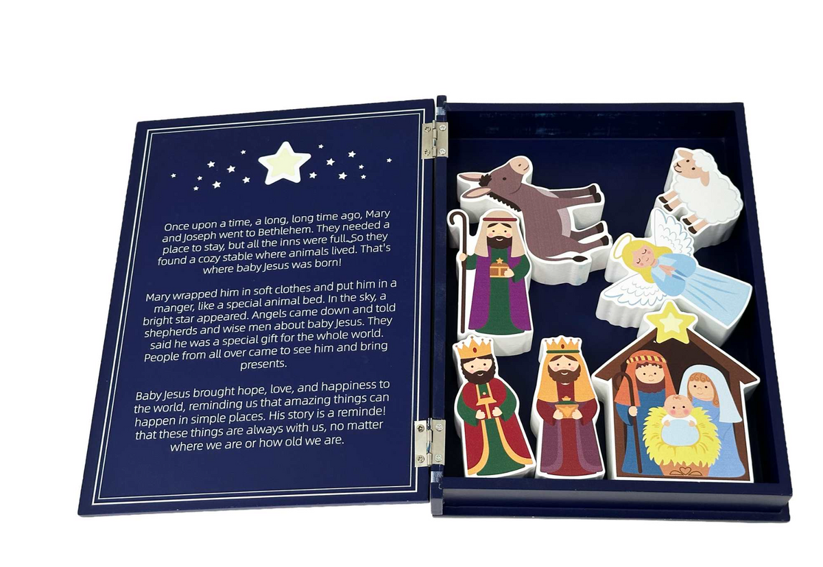 An open Bible story board book with a navy blue cover and interior, showing printed text on one side and colorful illustrated cutout figures on the other, including a bear, wise men, shepherds, and baby Jesus in a stable.